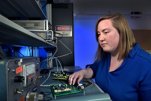 一个穿蓝色衬衫的白人妇女在实验室里摆弄收音机
